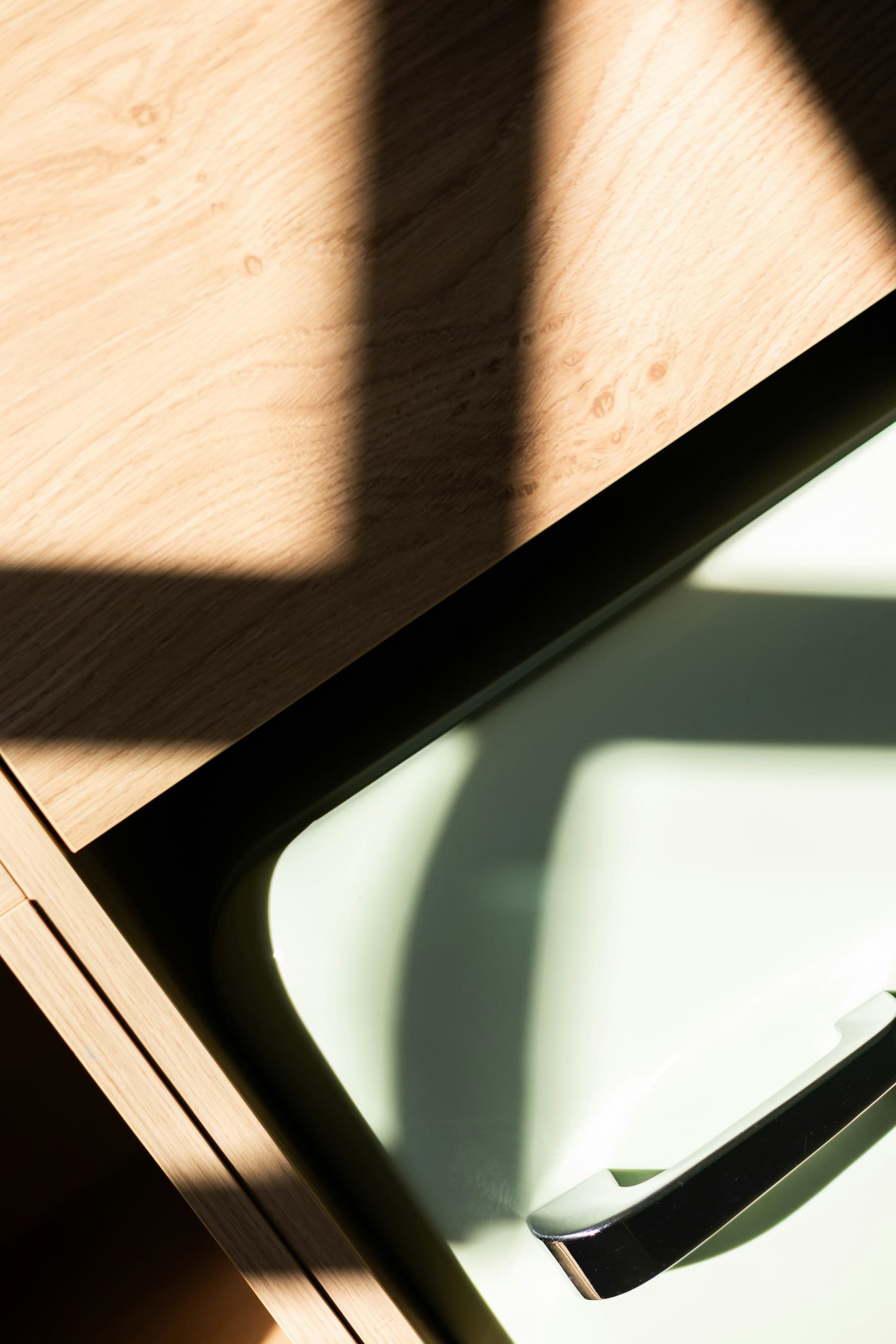 Raking daylight across a cabinet front and its inset handle
