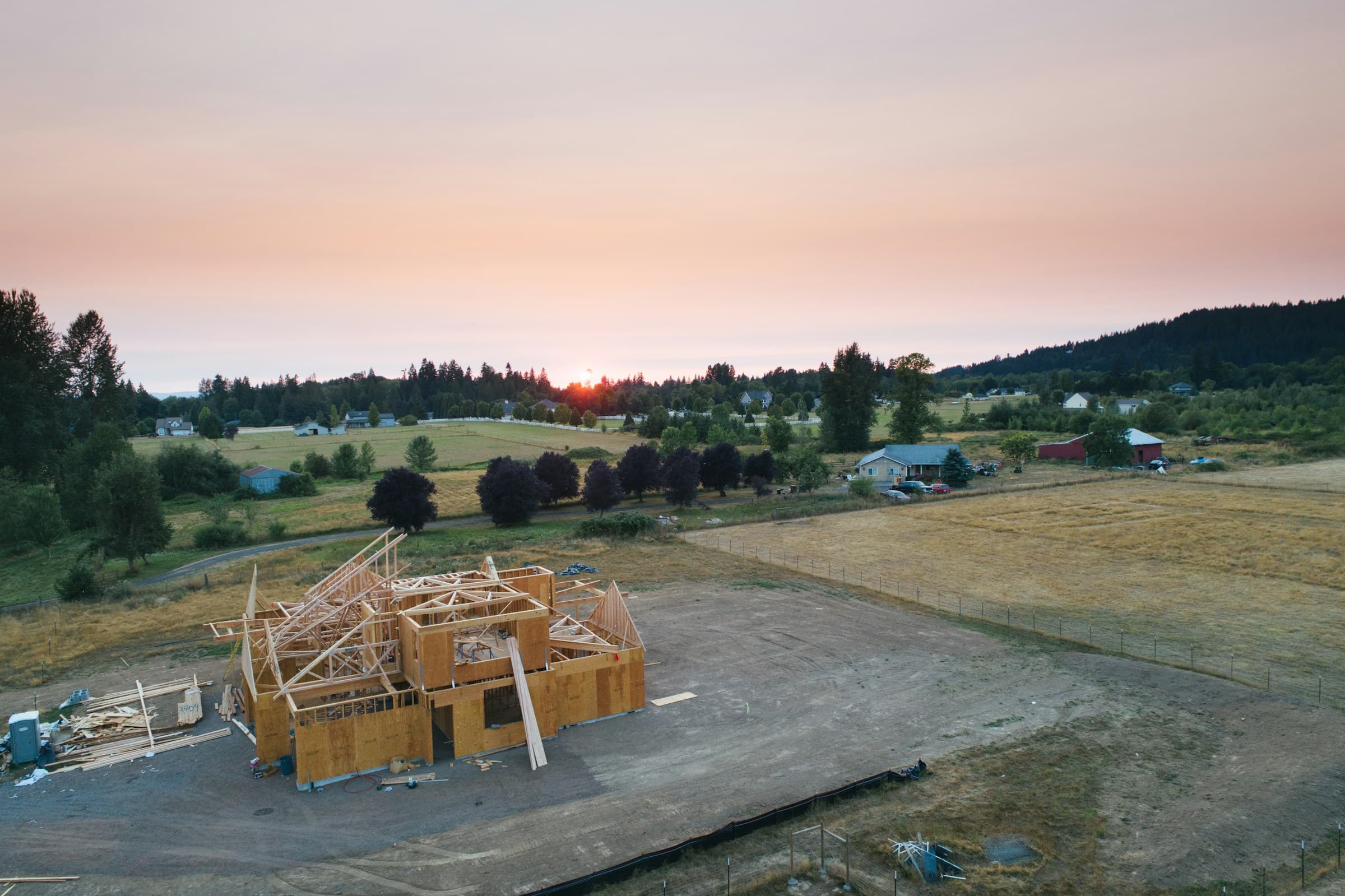 A house frame going up on open rural land at dusk