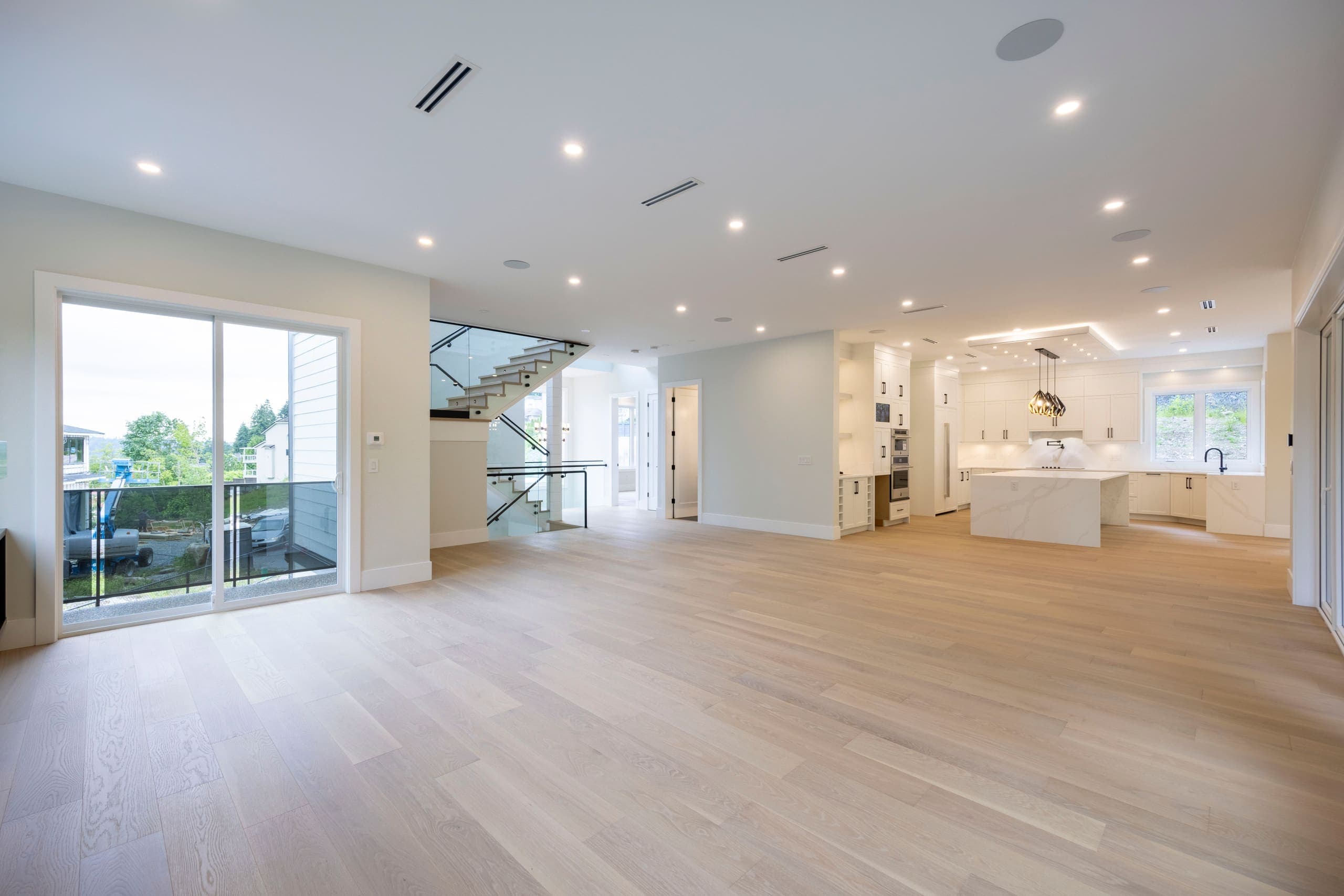 Great room open to the kitchen, stair and glazing beyond — The Monashee House
