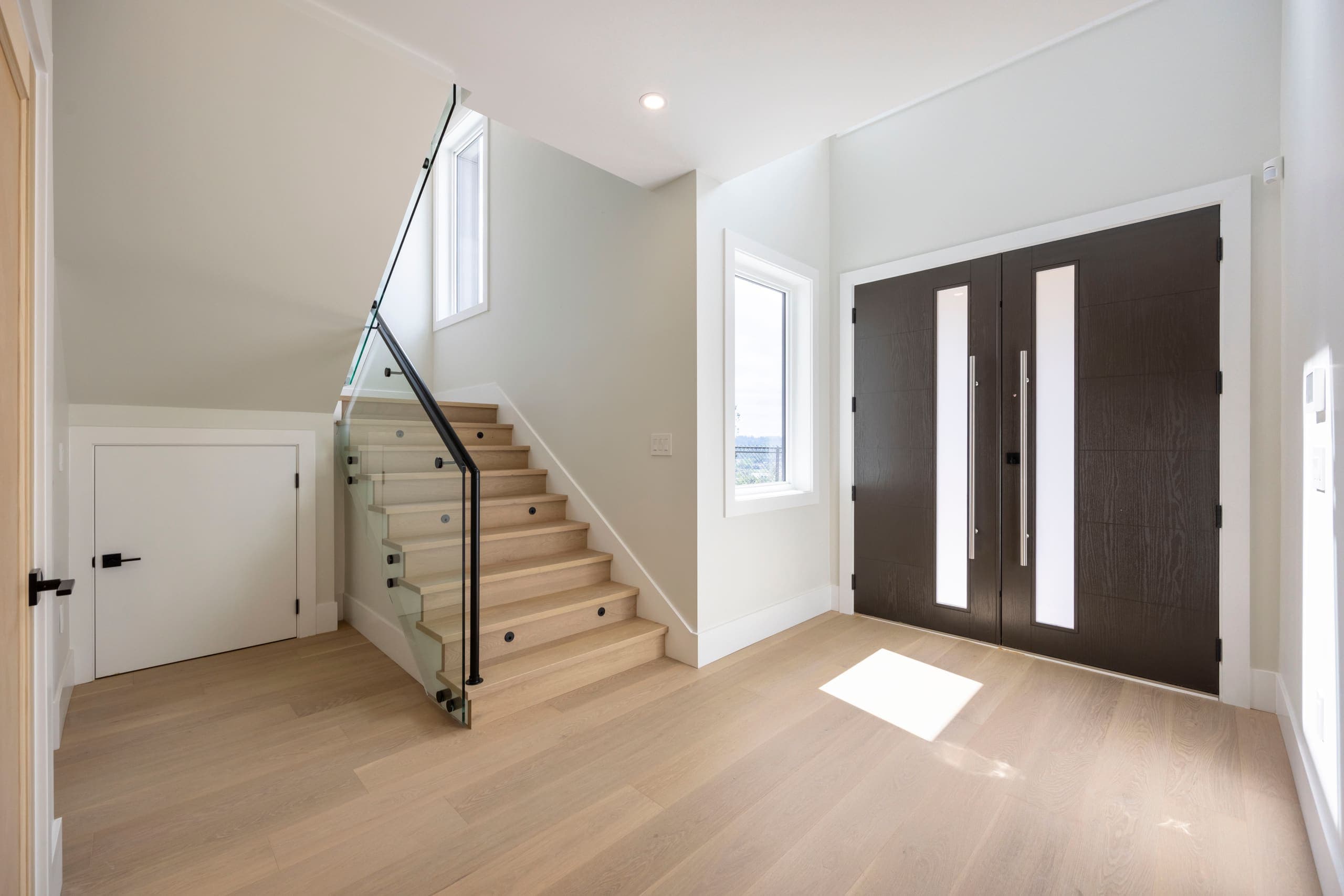 Entry hall with the open stair and dark double doors — The Monashee House