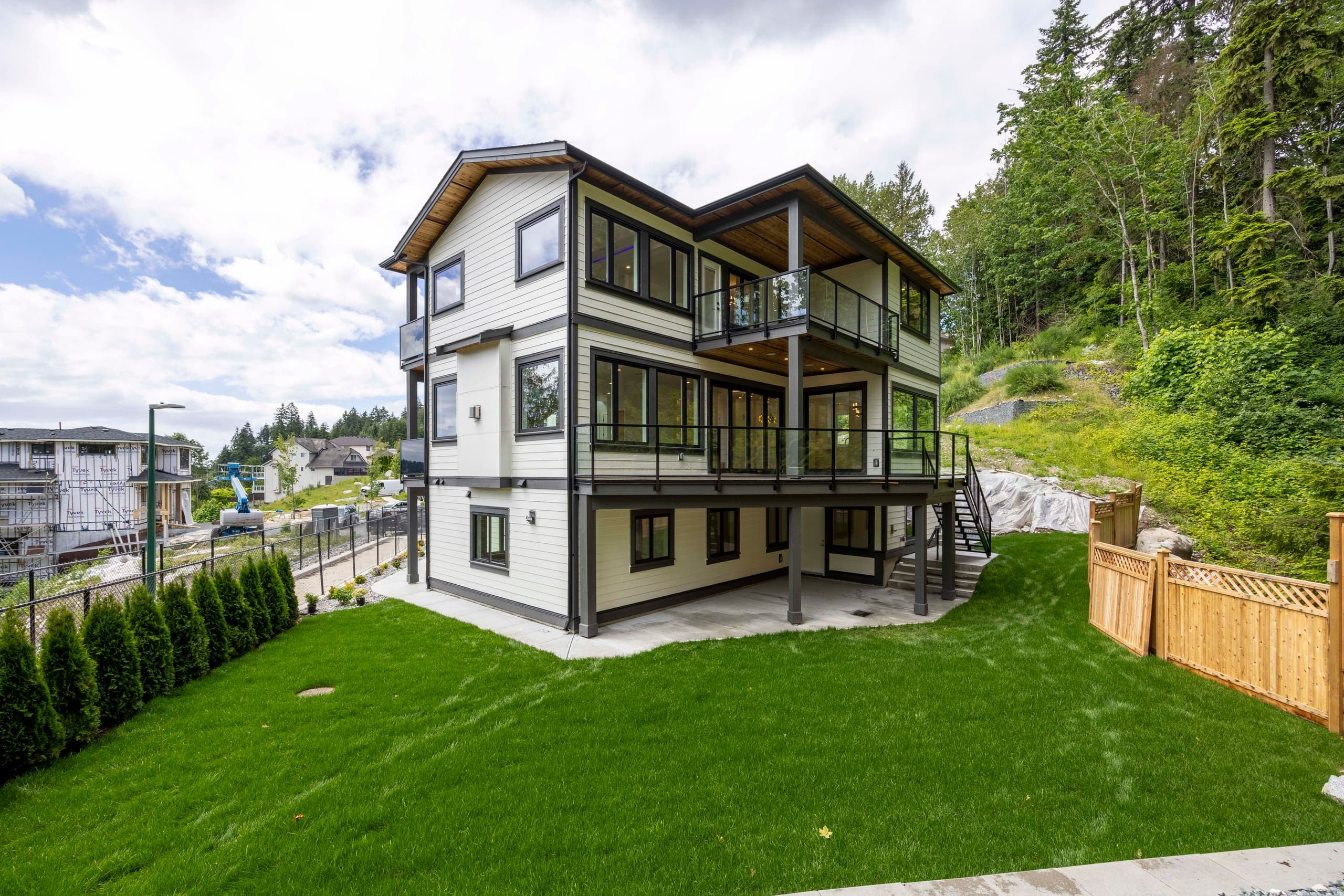 Rear elevation and lawn, decks stacked across the back — The Monashee House