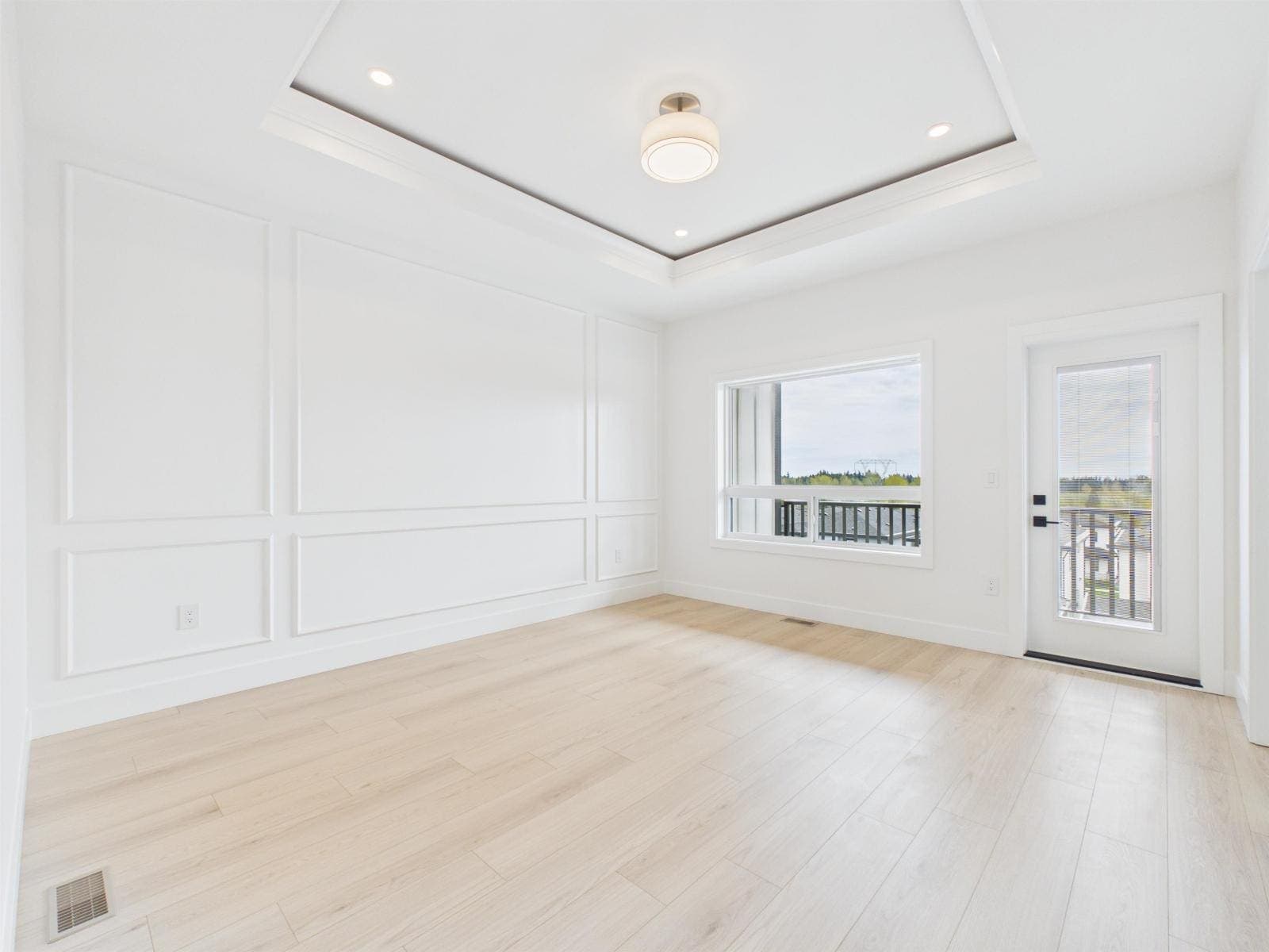 Primary bedroom with a panelled wall and balcony door — The Pacific Douglas Duplex